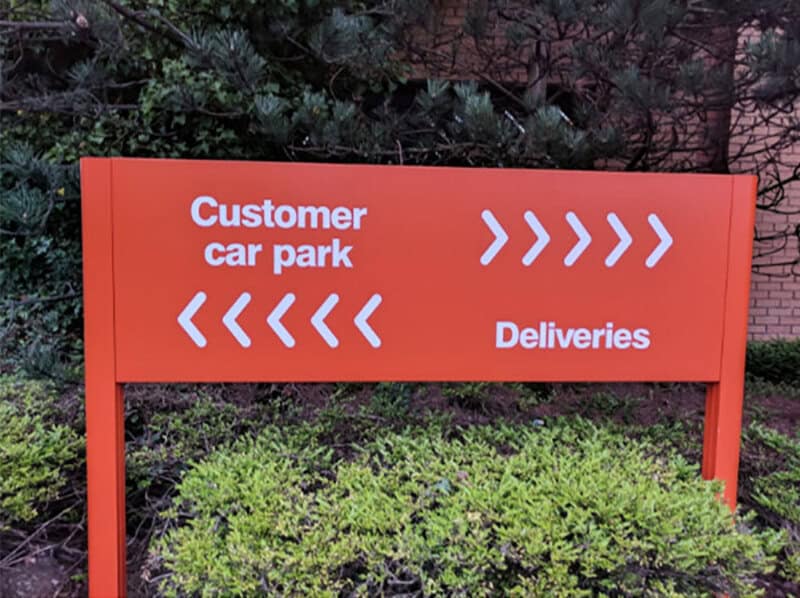 Sign for customer car park with arrows pointing both ways and 'Deliveries'.
