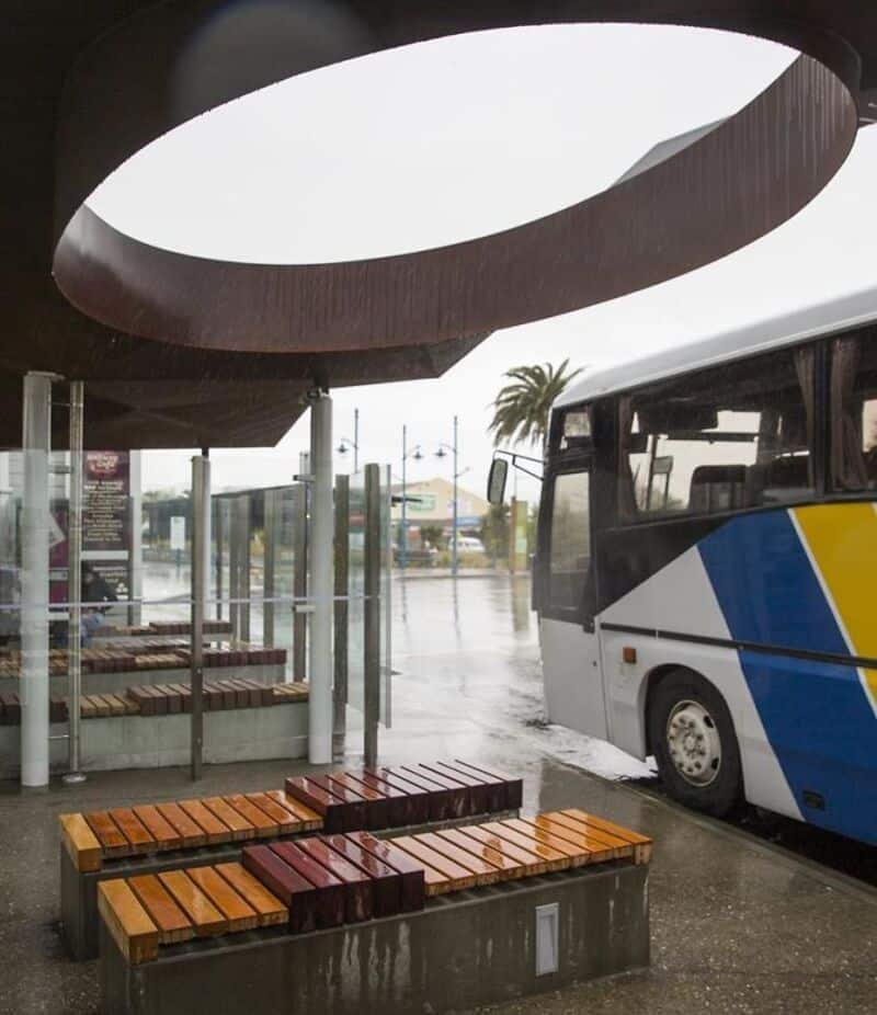 Bus parked under a modern architectural structure with circular opening.