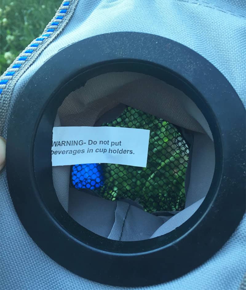 Warning label inside a cup holder says, 'WARNING- Do not put beverages in cup holders.'.