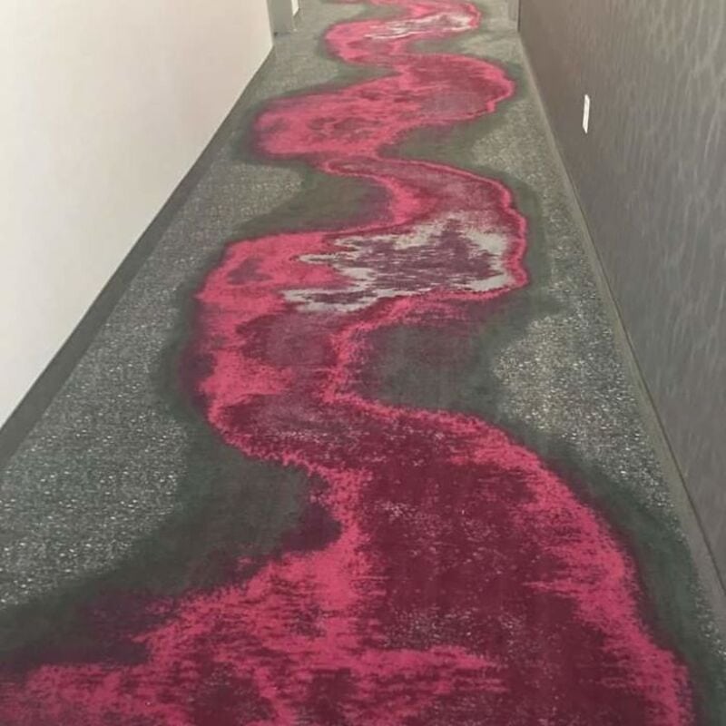 Colorful carpet with a pink and gray abstract pattern in a hallway.
