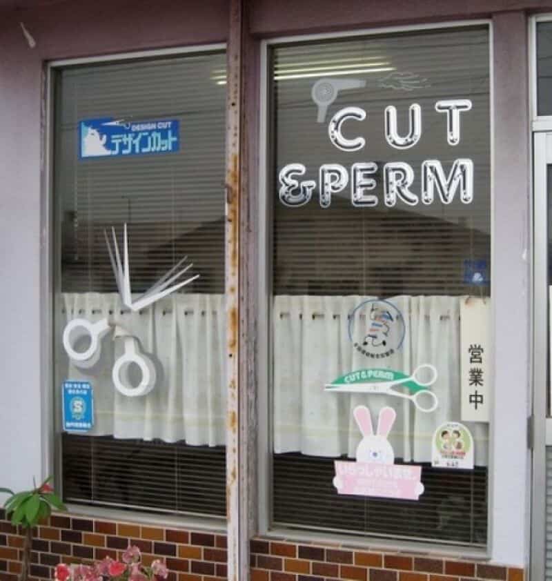 Sign for 'Cut & Perm' hair salon with scissors and bunny decoration.