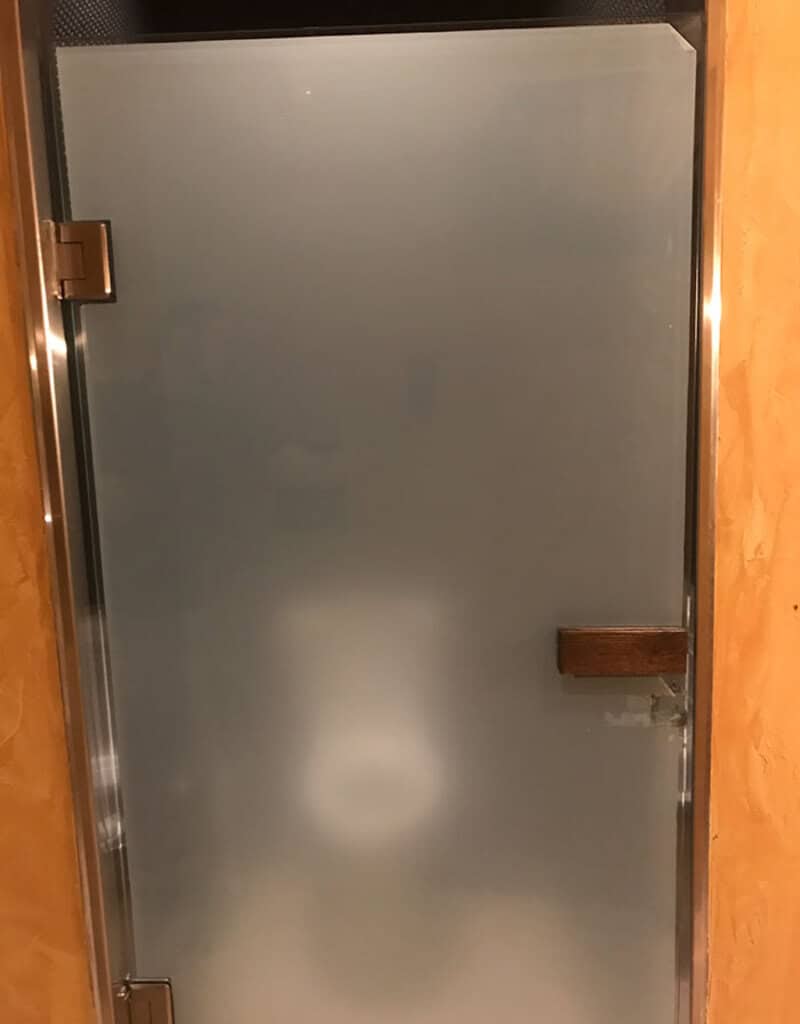Frosted glass door with a wooden handle and metal hinges.