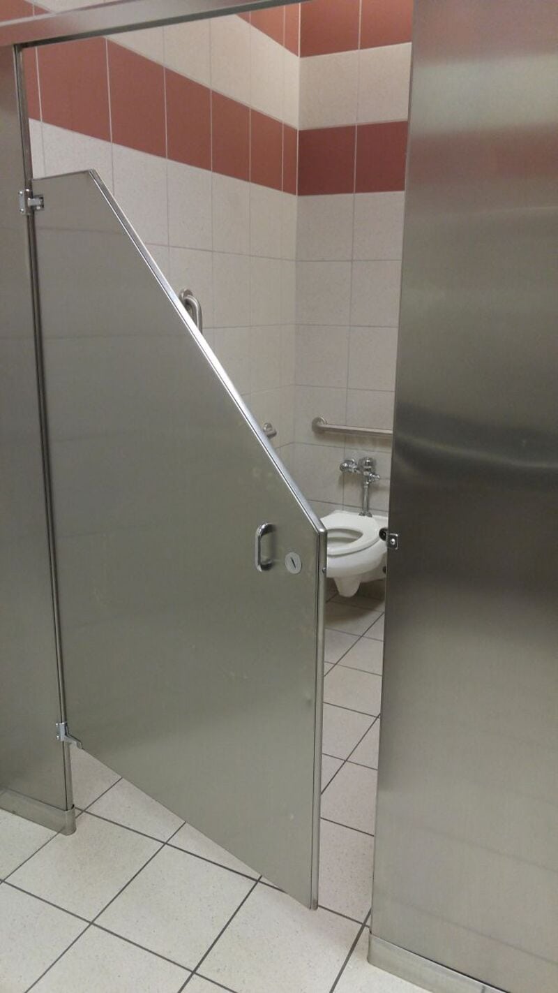 Bathroom stall door is open, revealing a toilet inside.