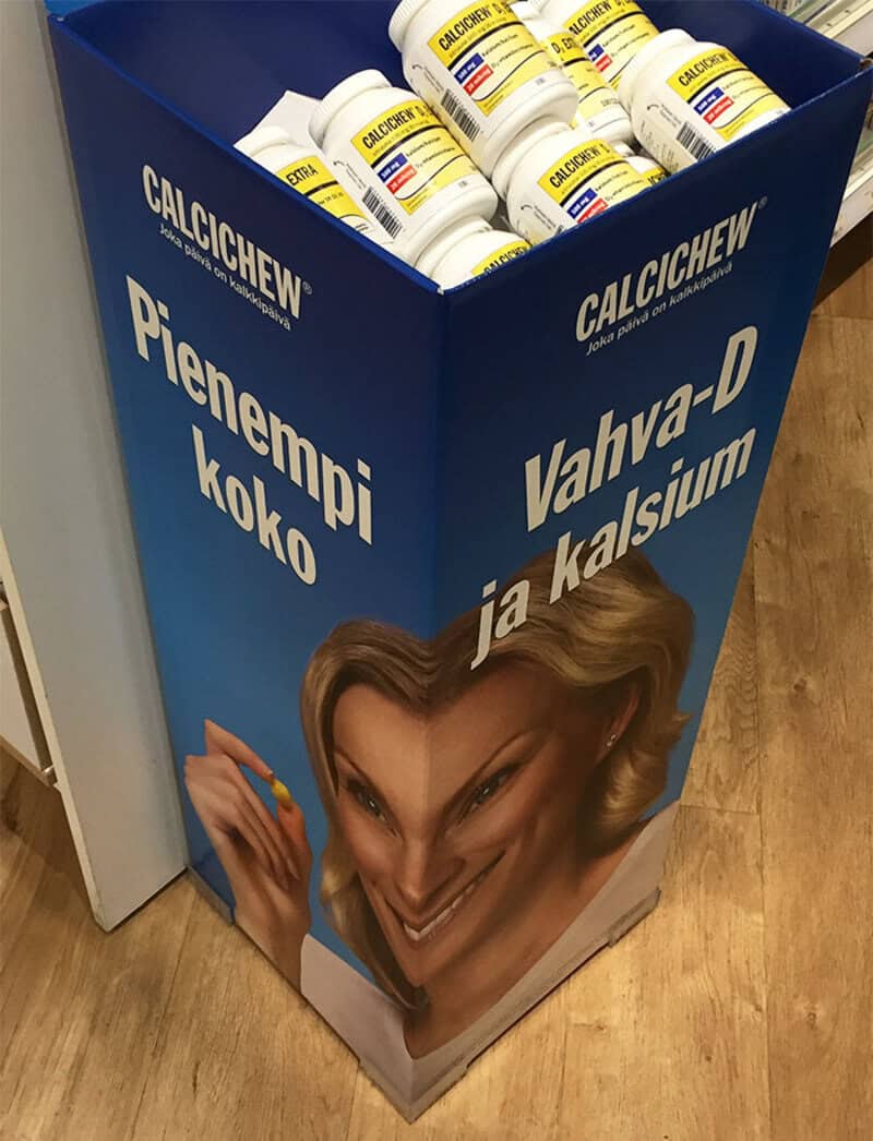 Display stand with bottles of calcium supplement and a distorted woman's face.