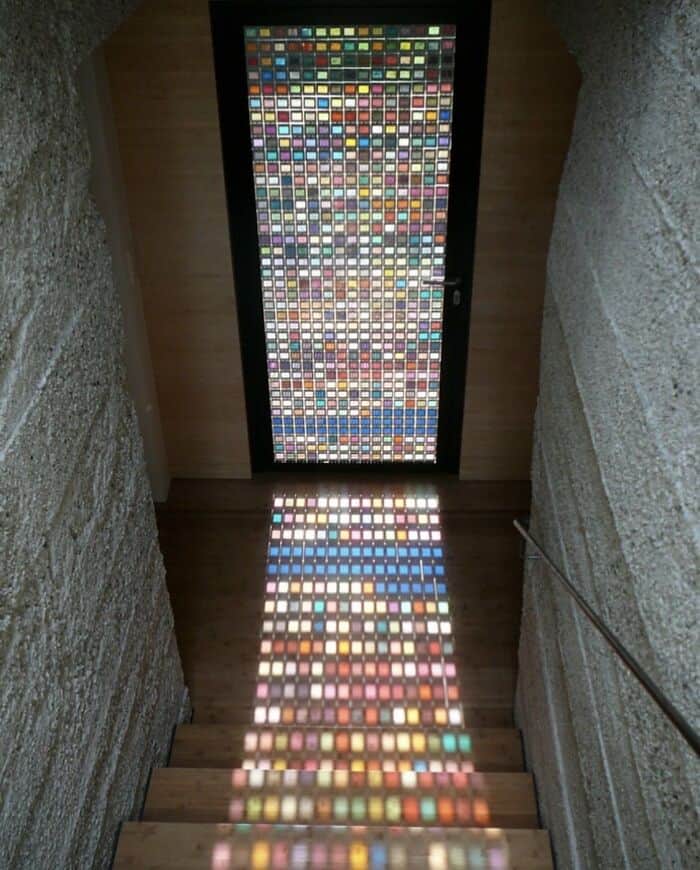 Colorful mosaic window at the top of a staircase with stone walls.