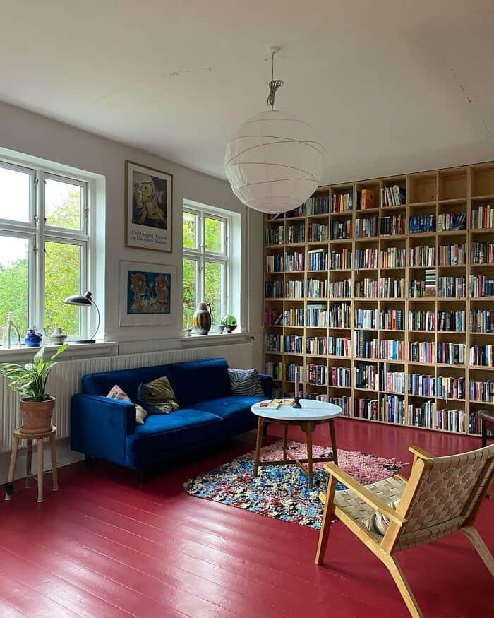 Cozy reading nook with blue sofa and large bookshelf in bright room.