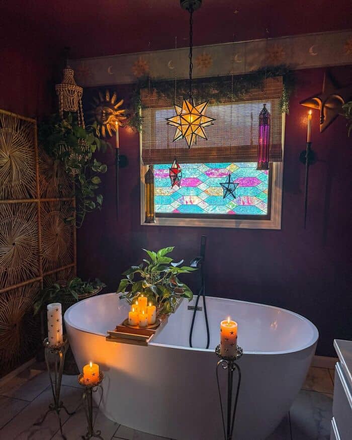 Cozy bohemian bathroom with candles, plants, and colorful stained glass window.