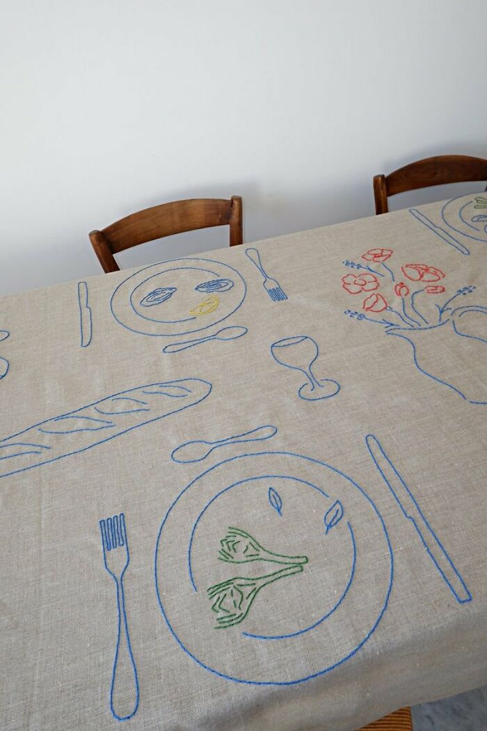 Tablecloth with hand-drawn food and tableware illustrations in blue, green, and red.