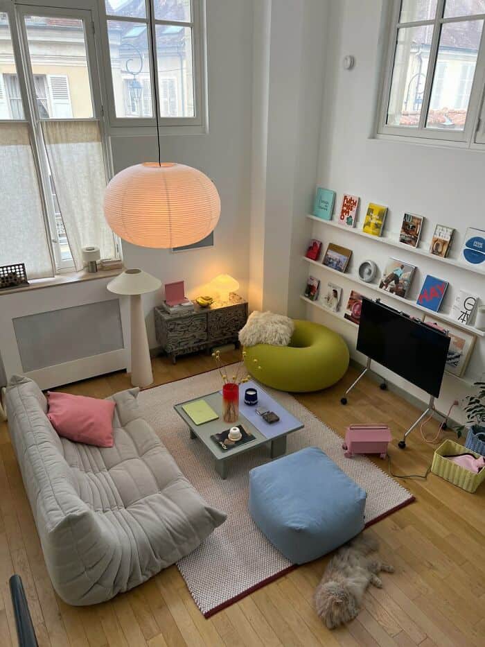 Cozy living room with a beige sofa, colorful cushions, and a large paper lantern hanging from the ce.