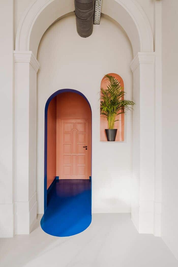 Modern interior doorway with colorful arch and potted plant.