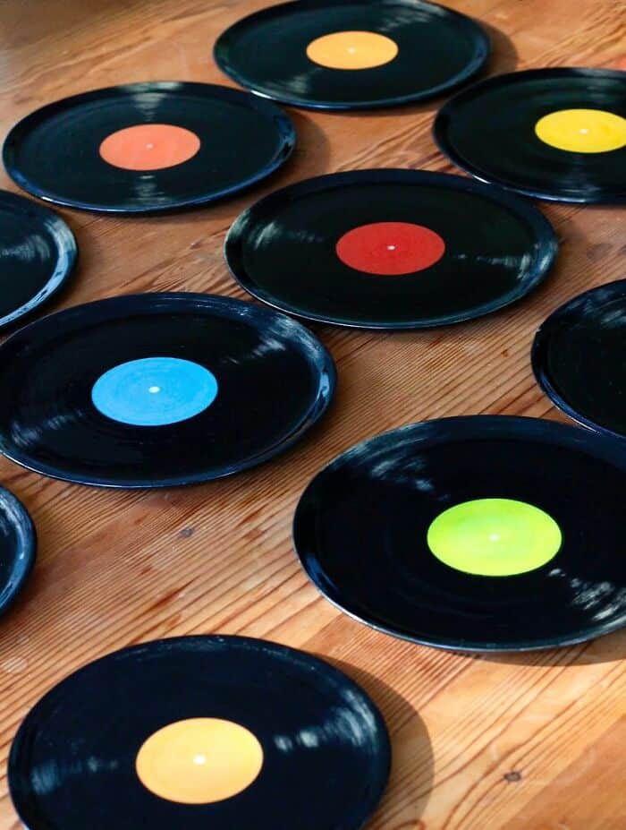 Brightly colored vinyl records on a wooden surface, each with a different vibrant center color.