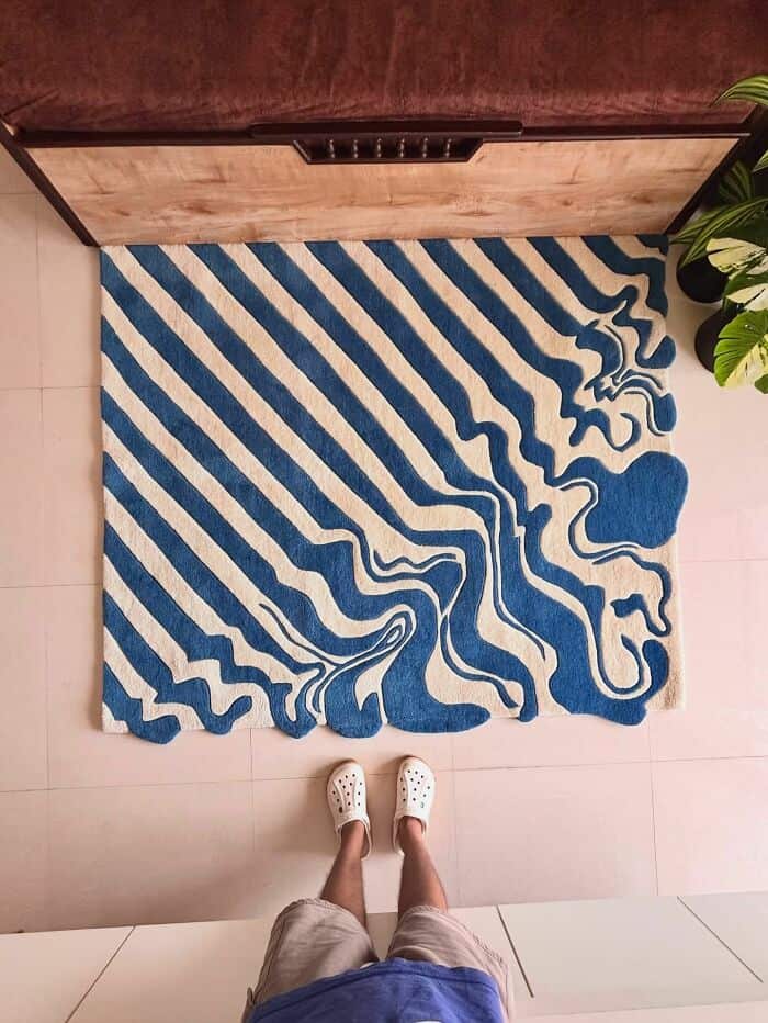 Blue and beige striped rug with wavy pattern in front of a wooden cabinet.