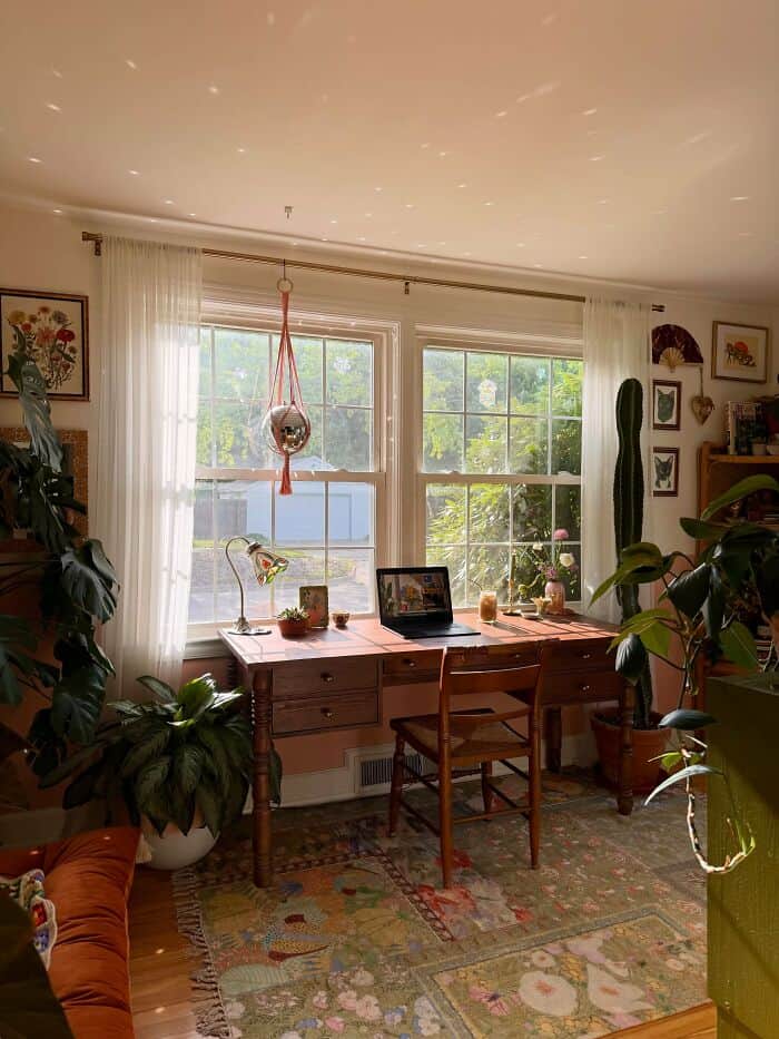 Cozy home office with large window, plants, and artwork.