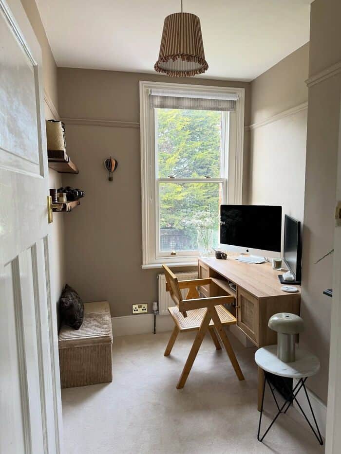 Cozy home office with a wooden desk, chair, computer, window view, and decorative elements.