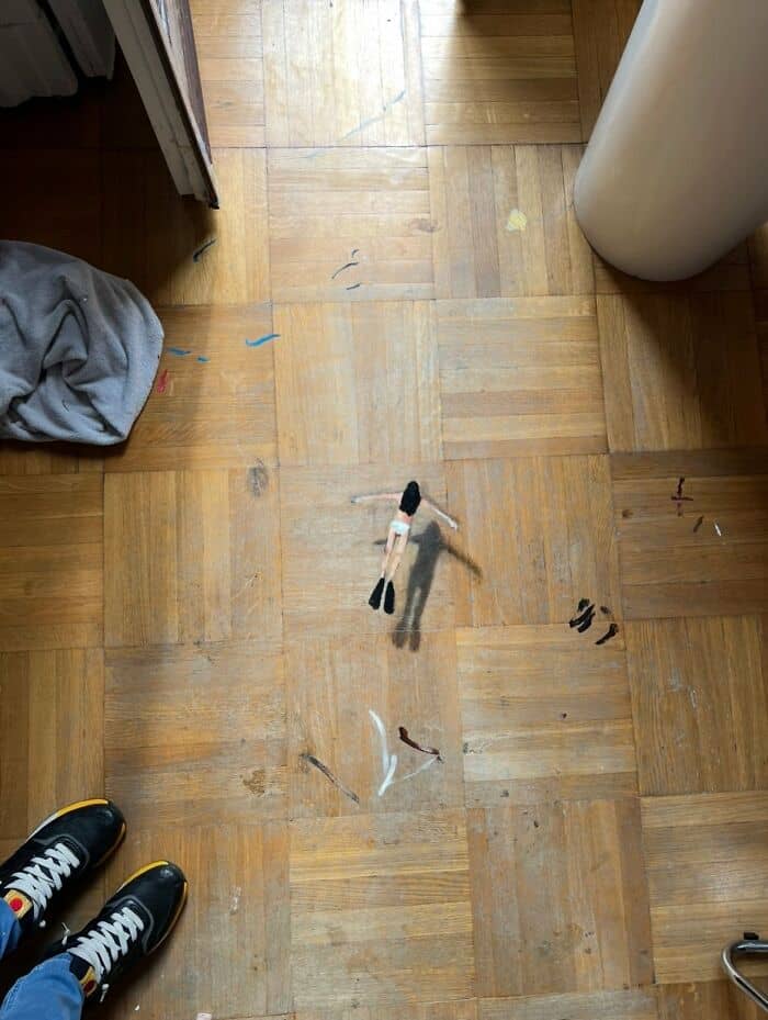 Small black and white toy figure on a wooden floor with paint marks.