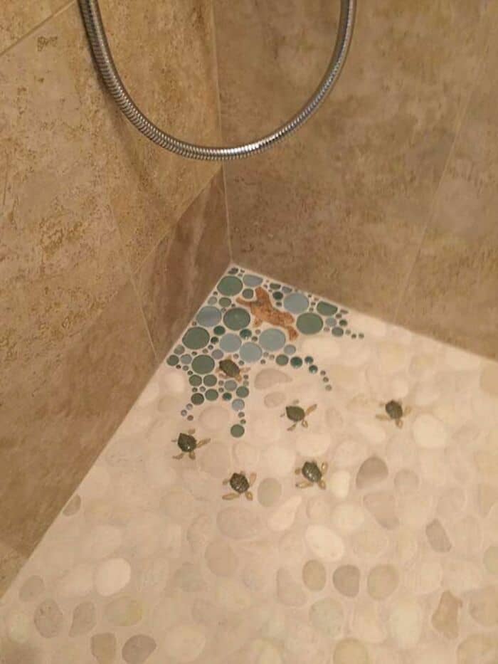 Small turtles and a butterfly on a pebble shower floor.