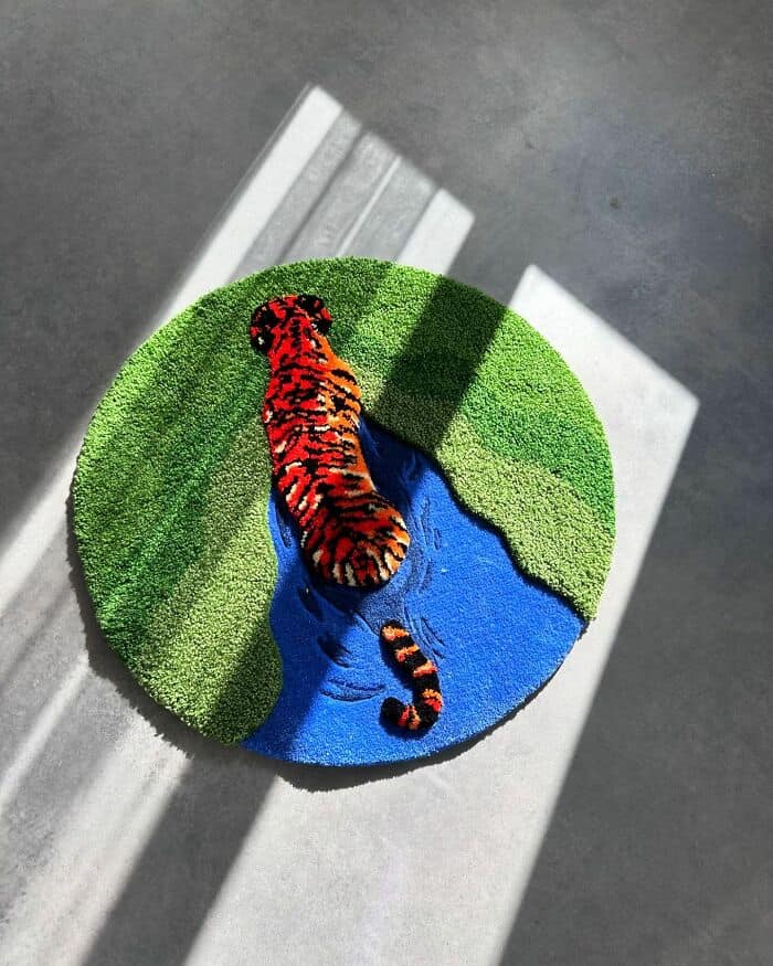 Tiger walking near a river on a round green and blue rug.