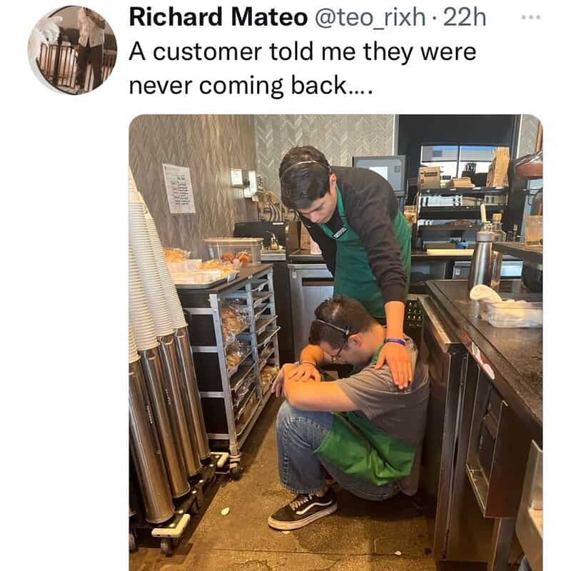 A customer sitting on the floor with his head down, being comforted by a staff member in a cafe or r.