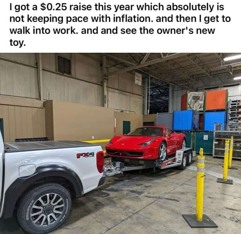 A white pickup truck towing a red sports car on a flatbed in an industrial warehouse.