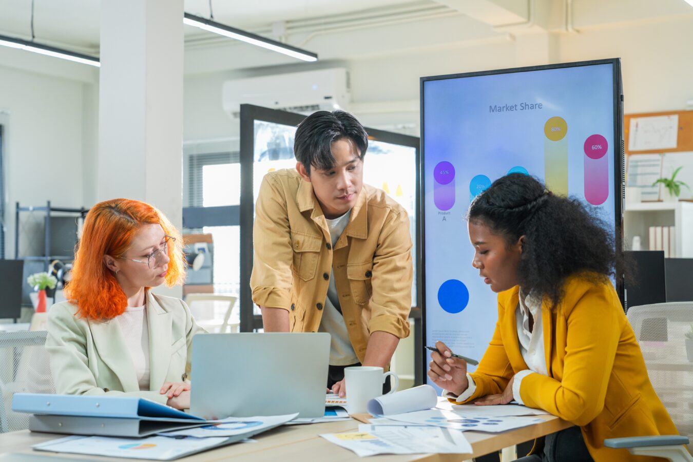 Team discussing market share in a modern office with a large screen.