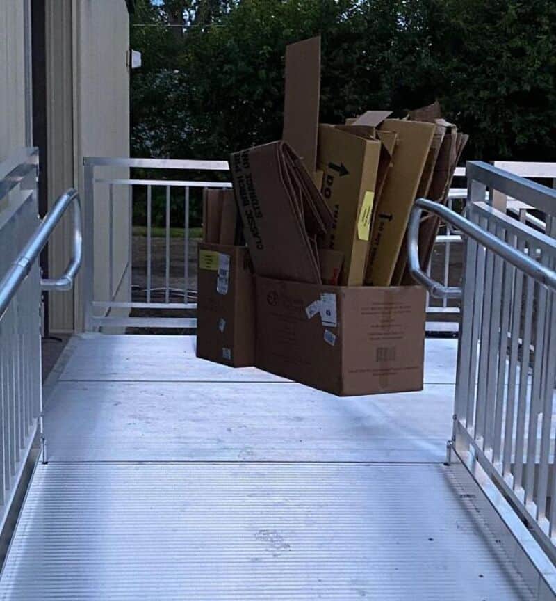 Cardboard boxes filled with flattened boxes on a porch with white railings.