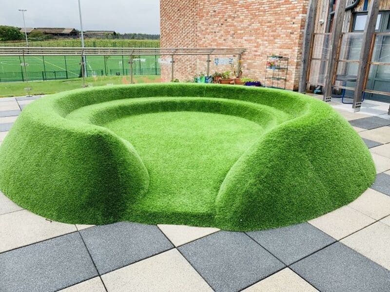 Unique circular green artificial grass seating area on a rooftop terrace.