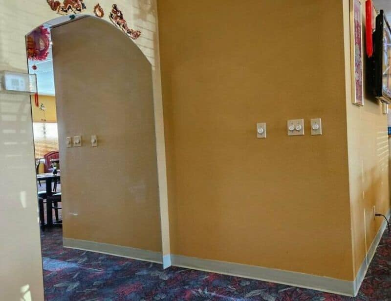 Empty room with beige walls, electrical outlets, and a patterned carpet.