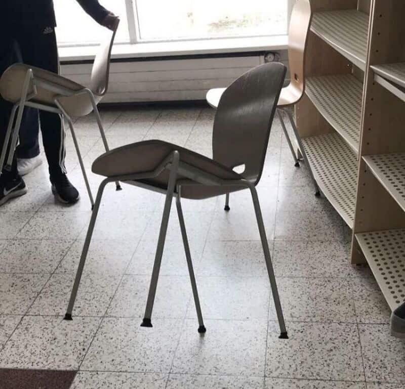 Chairs stacked and arranged in a room with a window and shelves.
