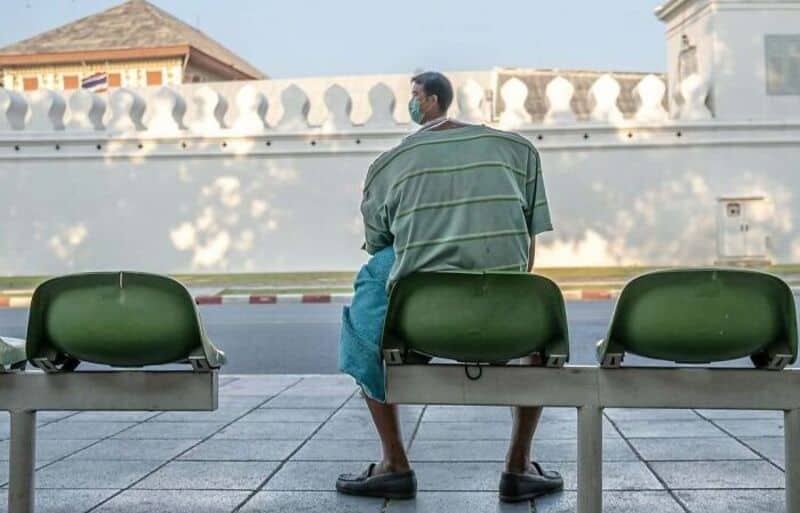 Man sitting alone on a bench at a bus stop, looking away.