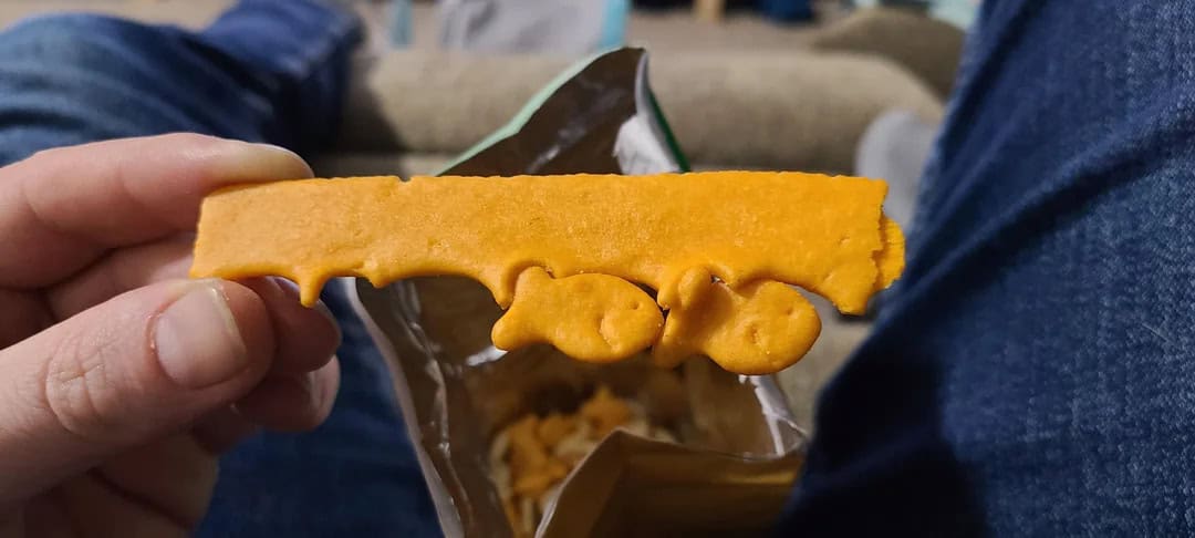Person holding a piece of cheese with a unique shape and texture.
