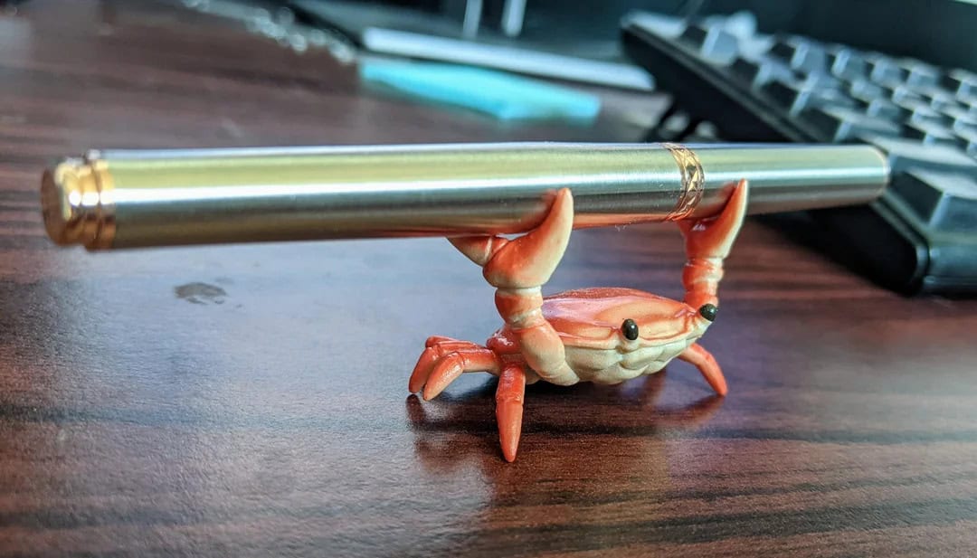 Crab holding a telescope on a wooden desk with a keyboard in the background.