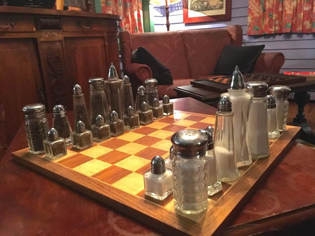 Glass salt and pepper shakers on a chessboard in a cozy room.