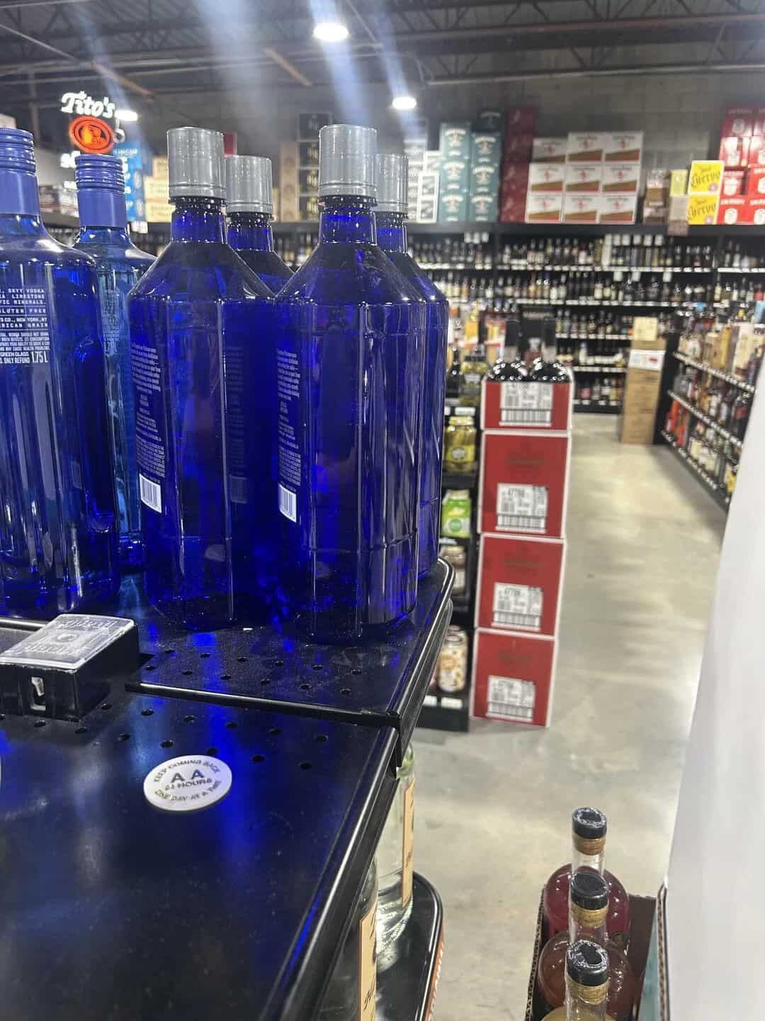 Blue bottles with silver caps on a store shelf in a warehouse store.