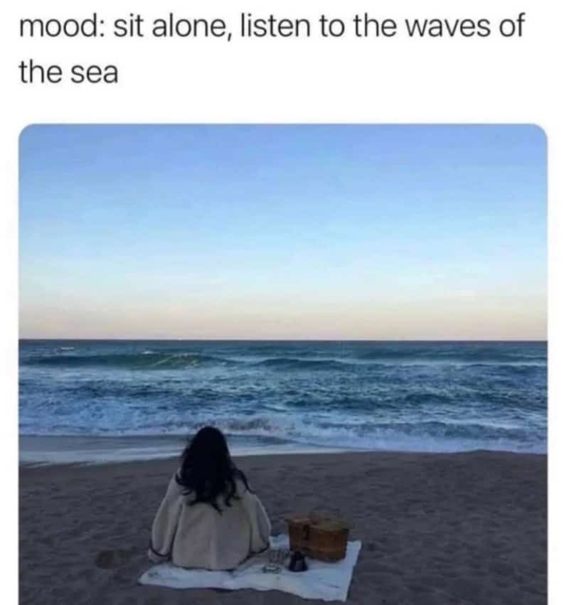 Person sitting alone on the beach listening to the waves of the sea.