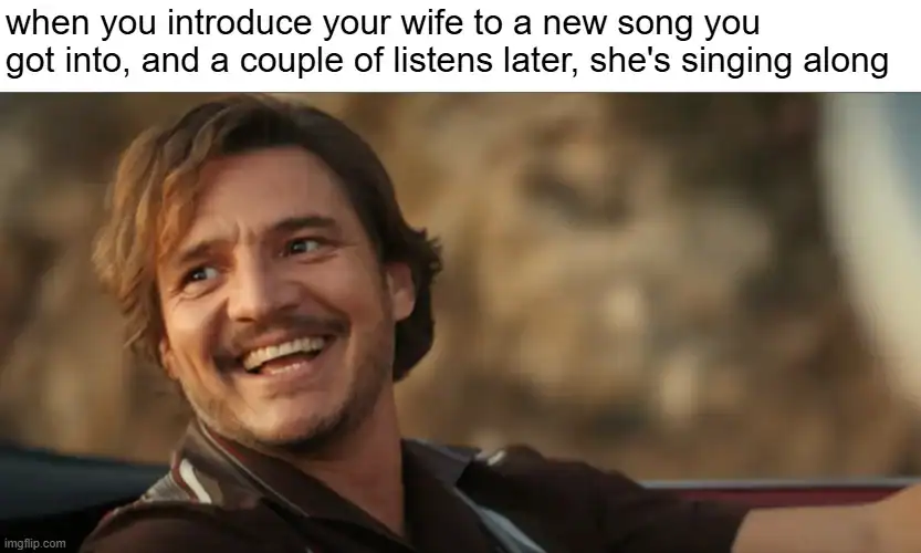 A man smiling while driving a car, with a scenic background.