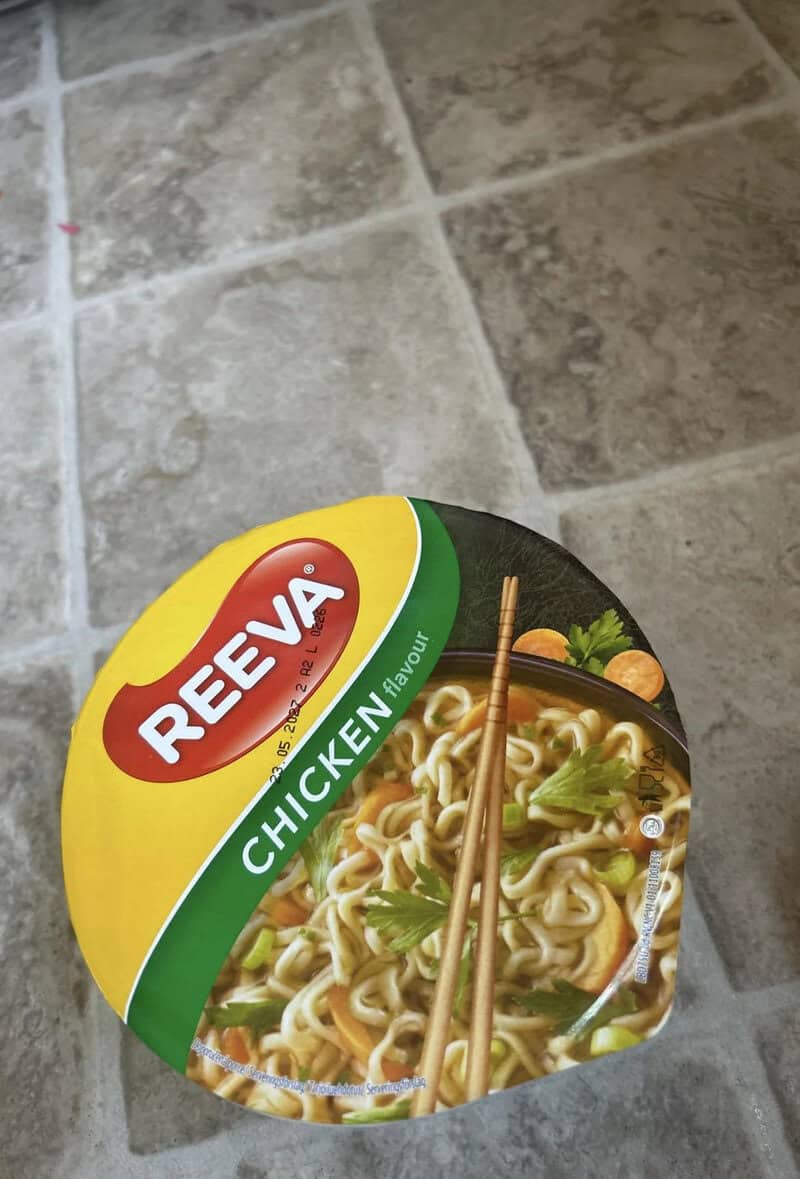ReeVita Chicken flavor instant noodles cup on tiled floor.