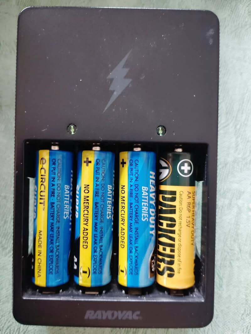 AA batteries in a battery compartment with a lightning bolt symbol on the cover.