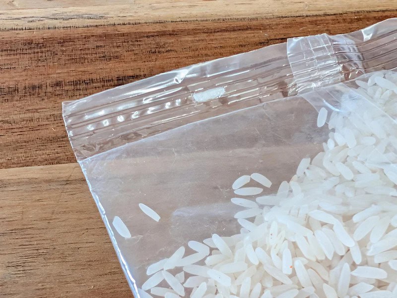A bag of uncooked white rice on a wooden surface.
