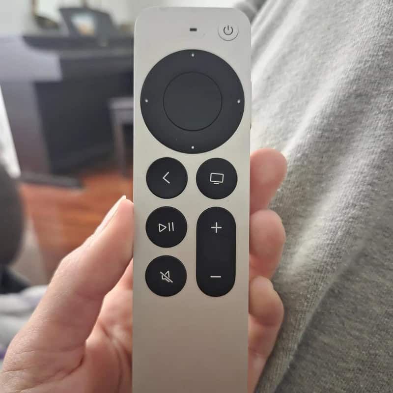 Remote control with various buttons, held in hand.