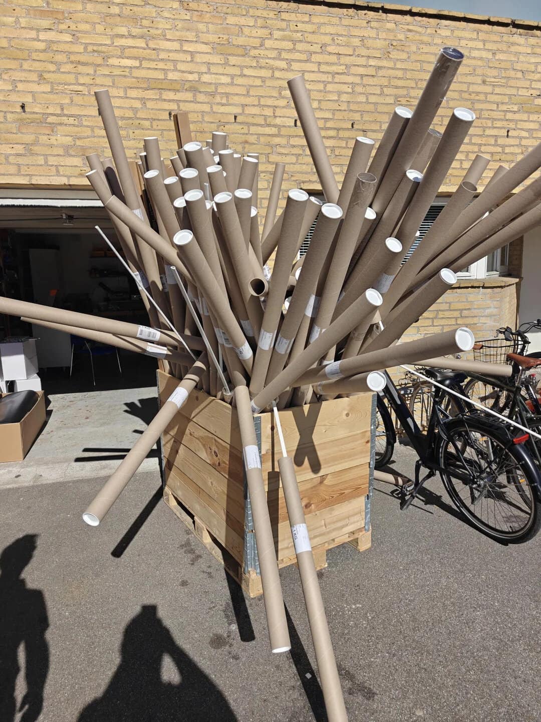 Piles of cardboard tubes in a wooden crate outside a building.
