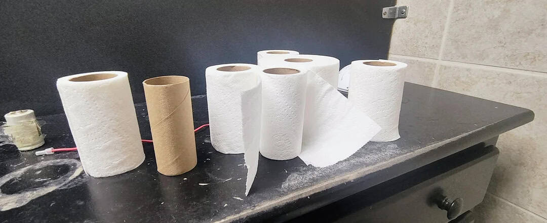 Rolls of toilet paper and paper towels on a black countertop.