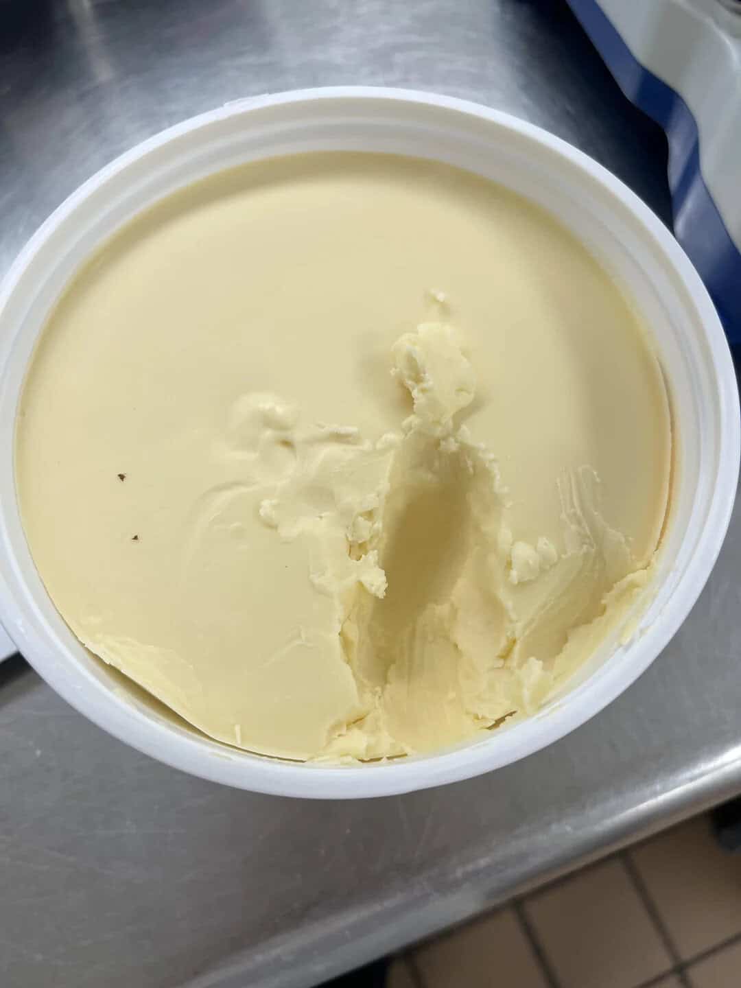 Close-up of a tub of vanilla ice cream with a scoop taken out.