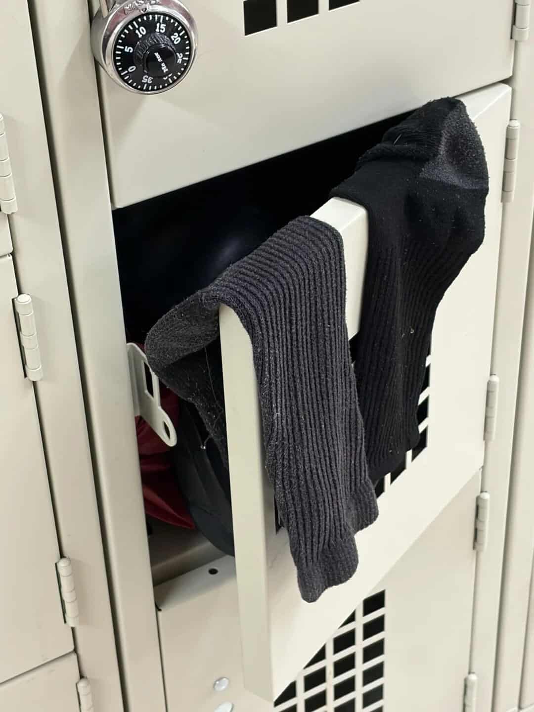 Socks hanging on a locker door with a combination lock above.