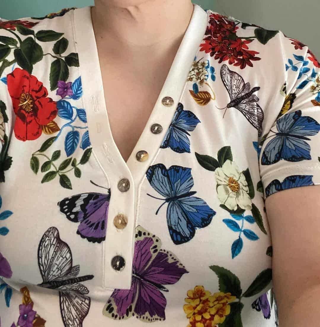 Close-up of a floral and butterfly patterned shirt with buttons.