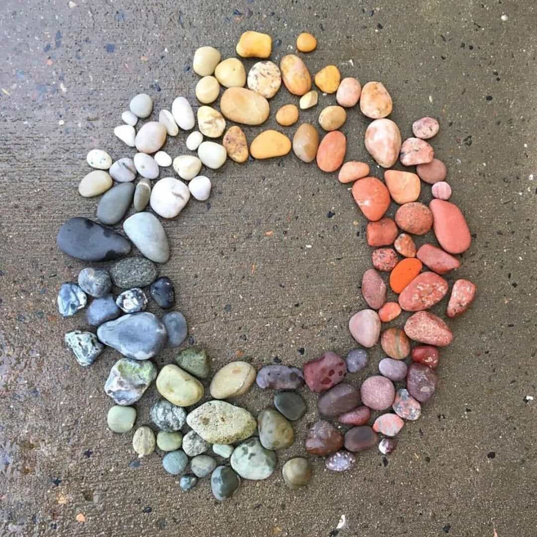 Colorful stones arranged in a circle on the sand, part of a beach finds collection.