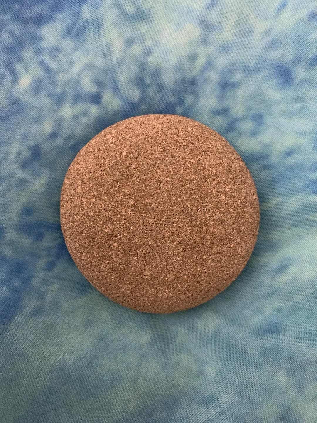 Round brown stone on blue fabric background.