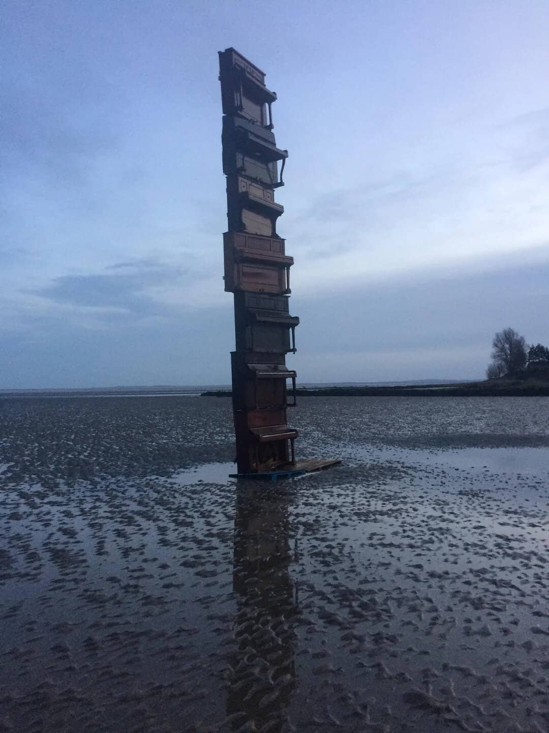 Stack of old wooden crates balanced on a beach at low tide.