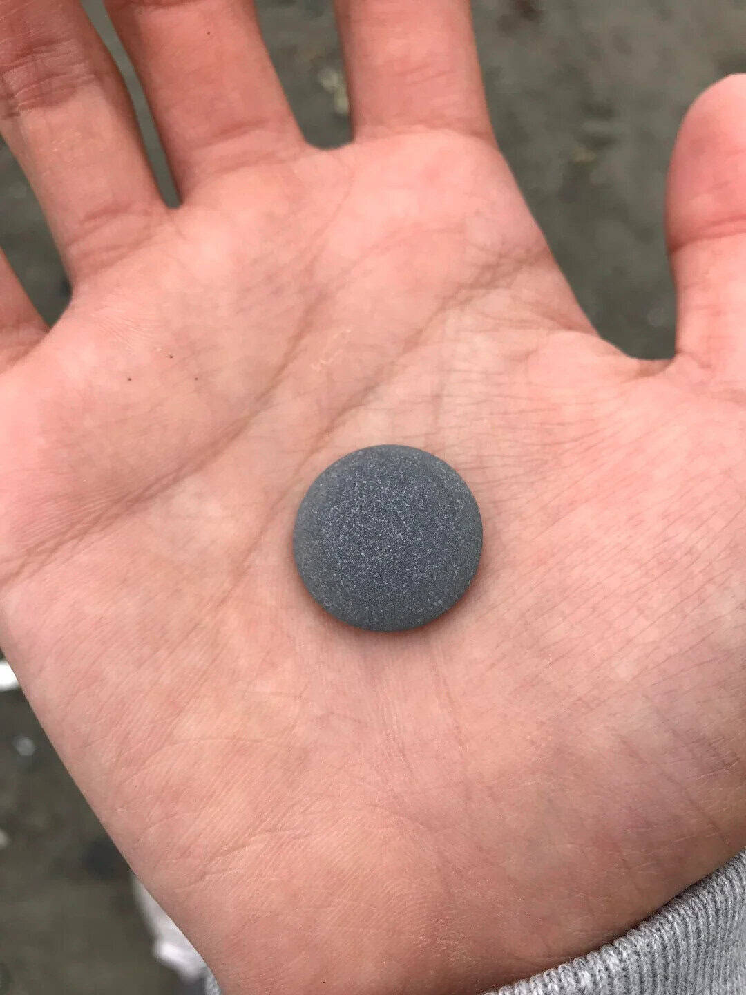 Smooth, dark gray stone on a person's open palm.