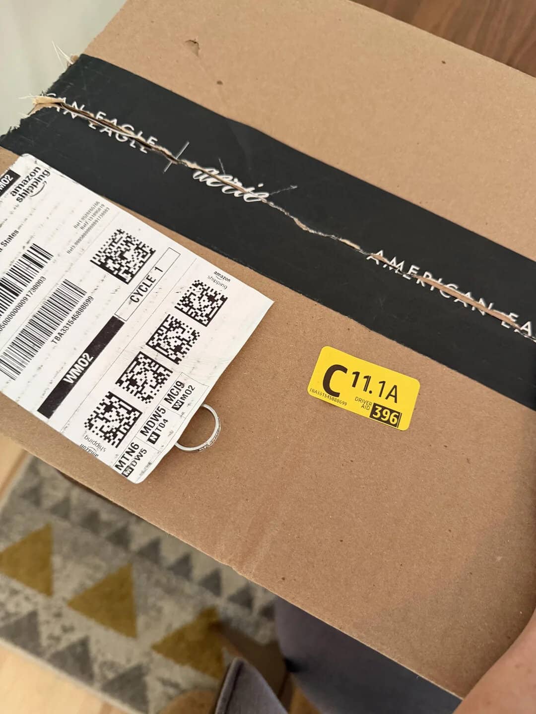 Cardboard box with torn black tape and shipping labels, yellow C sticker visible.