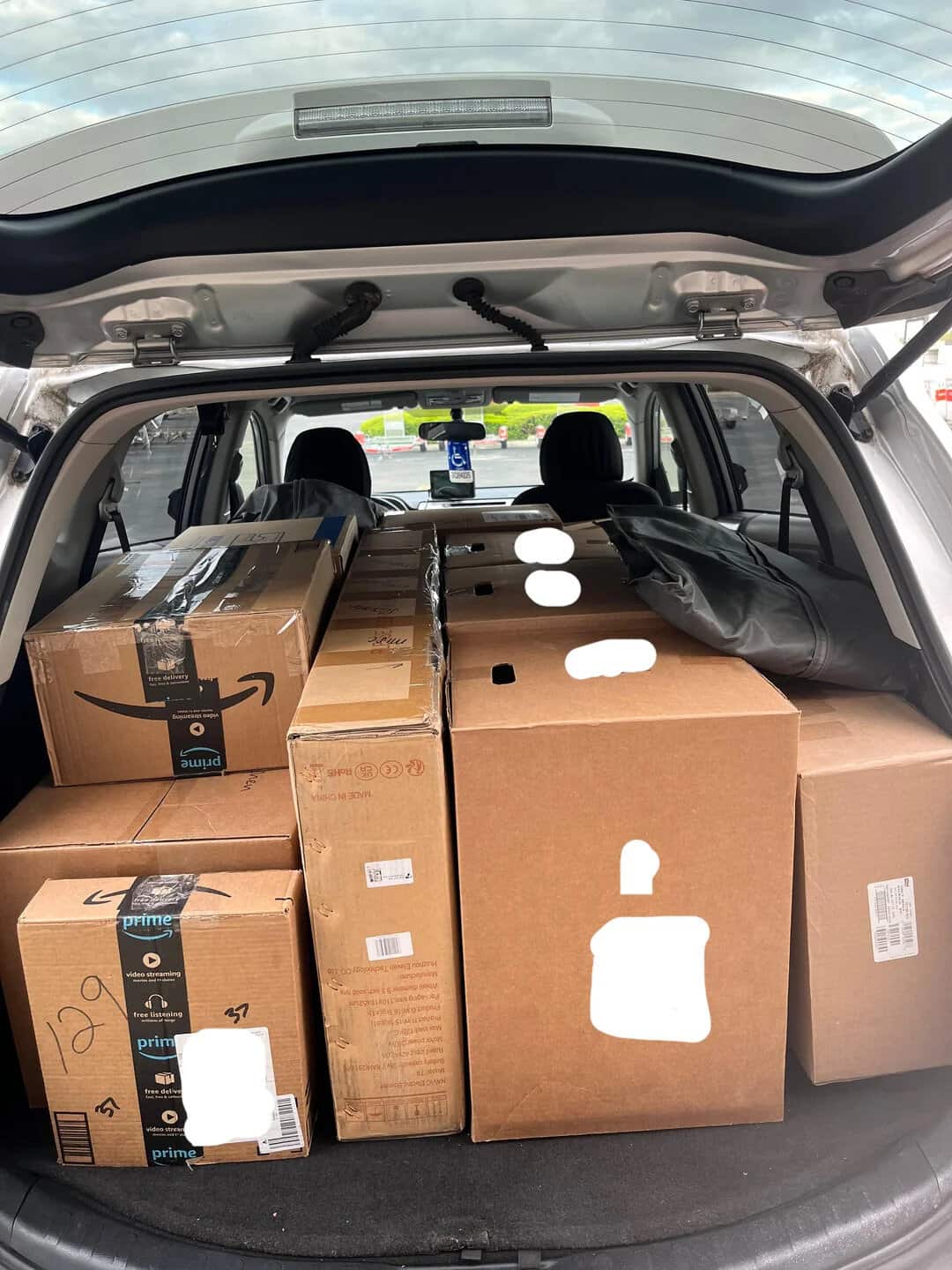 Amazon Prime boxes and a black bag loaded in the trunk of a car.